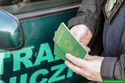 Fukcjonariusz SG trzymający paszport 