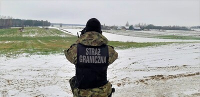 funkcjonariusz SG obserwujący teren przez lornetkę 