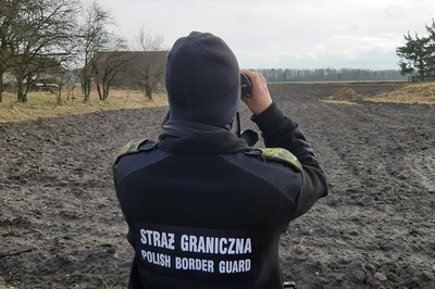 funkcjonariusz SG obserwujący granicę przez lornetkę 