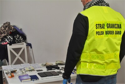 funkcjonariusz SG w kamizelce z napisem Straż Graniczna, zatrzymane przedmioty podczas przeszukania 
