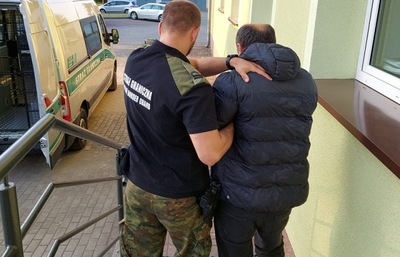Funkcjonariusz SG doprowadza jednego z 38 cudzoziemców, których zatrzymano w drodze do Niemiec 