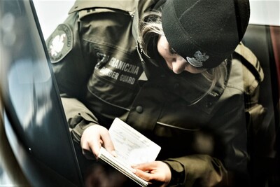 Funkcjonariuszka SG przegląda paszport 