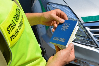 Funkcjonariusz SG trzyma w rękach ukraiński paszport 