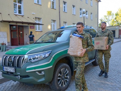 Funkcjonariusze niosą zebrane dary dla powodzian. 