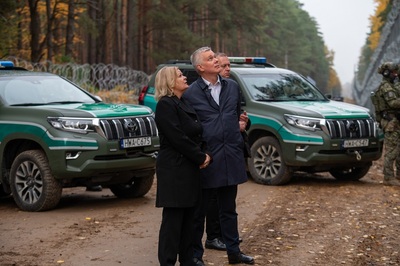 Ministrowie Spraw Wewnętrznych Polski i Niemiec przy barierze na granicy polsko-białoruskiej, na tle dwóch pojazdów służbowych Straży Granicznej. Ministrowie Spraw Wewnętrznych Polski i Niemiec przy barierze na granicy polsko-białoruskiej, na tle dwóch pojazdów służbowych Straży Granicznej.