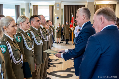 Uroczystość z okazji Narodowego Święta Niepodległości w Komendzie Głównej Straży Granicznej Minister Spraw Wewnętrznych i Administracji gratuluje odznaczeni funkcjonariuszowi Straży Granicznej.