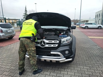 Mercedes poszukiwany w Niemczech został odzyskany przez Straż Graniczną Funkcjonariusz Straży Granicznej kontroluje samochód.