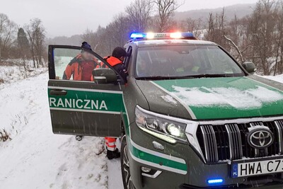 Pojazd Straży Granicznej i stojący obok ratownicy. Pojazd Straży Granicznej i stojący obok ratownicy.