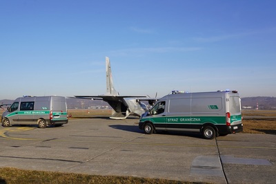 Dwa pojazdy Straży Granicznej obok samolot transportowy Dwa pojazdy Straży Granicznej obok samolot transportowy